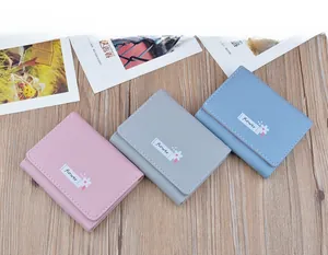 Top view of three pastel-colored soft leather tri-fold wallets with floral prints