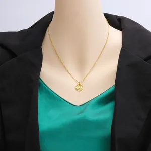 Detail shot of a hammered gold disk pendant necklace on a black and green outfit.