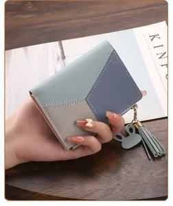 Detail view of a slim color-block women's short wallet with tassel and bunny charm