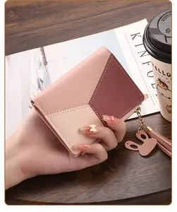 Close-up of a pink color-block short bifold wallet with a cute rabbit tassel charm