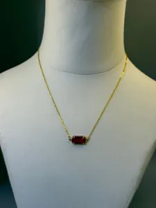 Elegante collana placcata in oro 18 carati con pendente radioso in pietra portafortuna rossa.