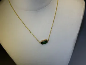Primo piano dettagliato di un'elegante collana con gemma ovale verde e catena placcata oro 18k