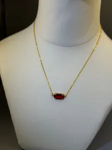 Dettaglio di una collana placcata oro 18 carati con un ciondolo rettangolare in pietra rossa.