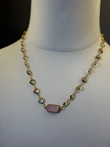 Dettaglio collana in oro 18 carati con elegante pietra rosa e gemme trasparenti lucenti