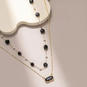 Elegante collana a doppio strato placcata oro 18K con pietre nere e perle bianche.
