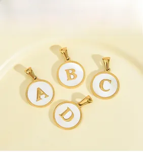 Close-up of gold stainless steel round pendants with white inlay and letters A, B, C, D