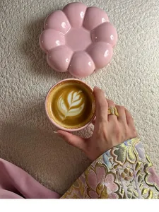 Aesthetic pink flower-shaped ceramic coffee cup set on white textured background