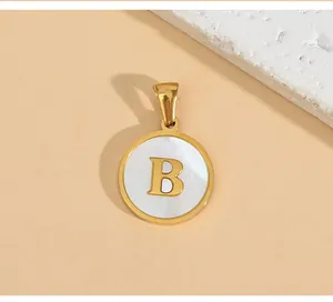 Close-up of a gold stainless steel circular pendant featuring a white inlay with a golden letter B.