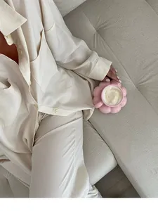Lifestyle view of a pink flower-shaped ceramic coffee cup set on a neutral sofa.