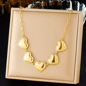 Close-up detail showing the gold-plated stainless steel necklace with five heart pendants