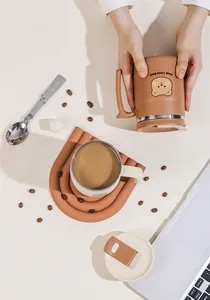 Detail of brown stainless steel bear mug set with folding spoon and lid on a desk