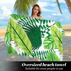 Dettaglio di un grande asciugamano da spiaggia con stampa di foglie tropicali Monstera.