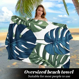 Asciugamano da spiaggia in microfibra con stampa di foglie di monstera tenuto da una modella