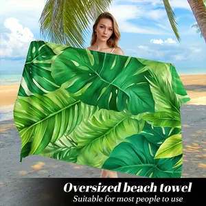Telo mare oversize in microfibra con stampa di foglie di monstera su spiaggia tropicale