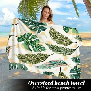 Dettaglio di telo mare oversize con stampa di foglie tropicali verdi e palma monstera
