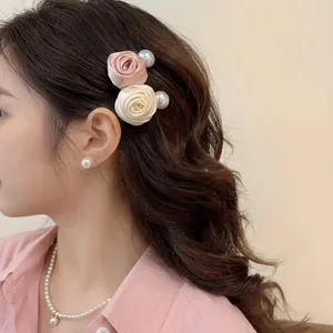 Detailansicht einer eleganten Haarspange mit Perlen und Satinrosen auf welligem Haar