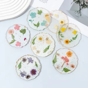Détail de dessous de verre en résine avec de vraies fleurs séchées et feuilles d'or.
