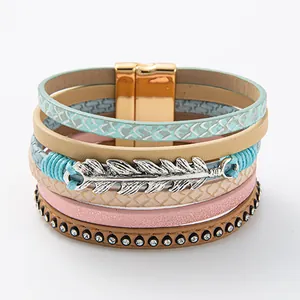Vista detallada de la pulsera de cuero multicapa bohemia con colgante de pluma de plata.
