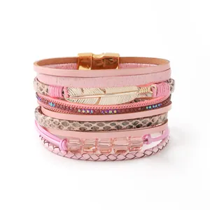 Primer plano de una pulsera de cuero rosa multicapa con dije de pluma dorada y cierre magnético