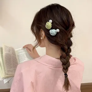 Elegante Rückansicht mit pastellfarbenen Rosen-Haarspangen und Perlen in einem Zopf.