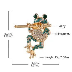 Detail view of frog brooch playing flute with rhinestone inlay and size metrics.