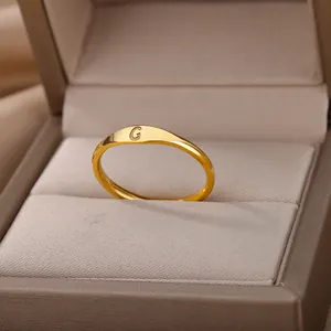 Macro view of a minimalist gold initial ring with an engraved letter G in box.