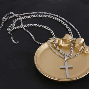 Close-up of double-layered silver cross necklace with Cuban and rope chain detail
