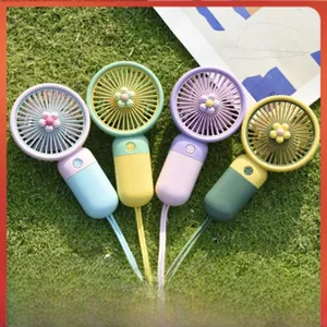 Quattro mini ventilatori portatili colorati con simpatici motivi a fiori su erba verde