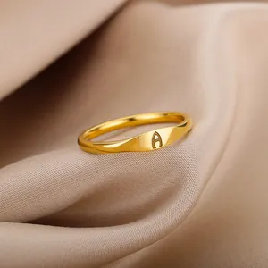 Macro view detail of gold signet ring with engraved letter A on soft silk background