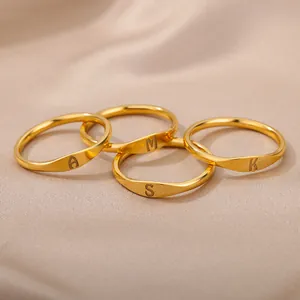 Close-up of four gold rings with engraved letters A, M, S, and K on silk fabric.