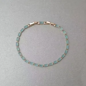 Vue de dessus détaillée d'un bracelet minimaliste en or rose avec des pierres baguette bleu clair