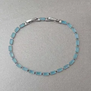 Gros plan d'un bracelet argenté délicat avec des pierres bleues claires rectangulaires.