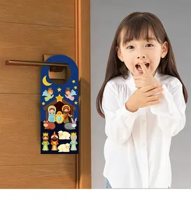 Kid demonstrating the DIY Christmas Nativity scene door hanger on a wooden door.