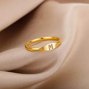 Detail view of a minimalist gold-plated signet ring featuring an engraved initial M