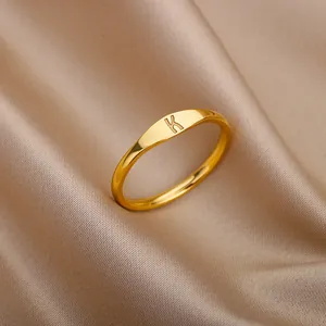 Close-up detail of a minimalist gold ring with an engraved letter K on satin