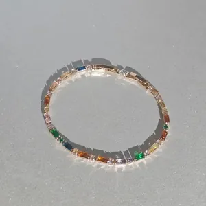Détail d'un élégant bracelet de tennis avec pierres précieuses arc-en-ciel sur fond gris