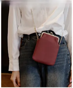 Detail of a burgundy genuine leather crossbody phone bag with gold chain strap on model