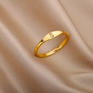 Close-up view of a minimalist gold ring featuring a finely engraved letter S on silk background