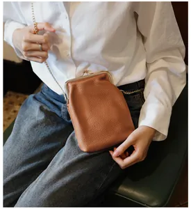 Close-up of genuine brown cowhide leather kiss-lock phone bag with chain strap