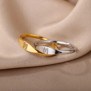 Detailed view of minimalist gold and silver rings with engraved initial M letter.