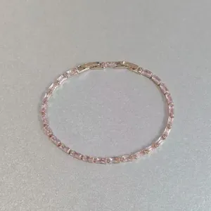 Détail d'un élégant bracelet en cristal rectangulaire rose avec une finition dorée