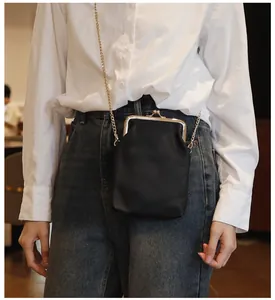On-body view of a black genuine leather kiss-lock phone bag with gold chain strap