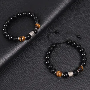 Close-up of 10mm black obsidian and tiger eye bead bracelets on a leather surface
