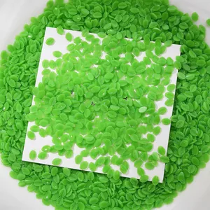 Gros plan détaillé sur des petits charmes d'ongles en forme de feuille verte pour manucure