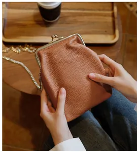 Close-up of genuine leather crossbody phone bag with vintage gold kiss-lock frame.