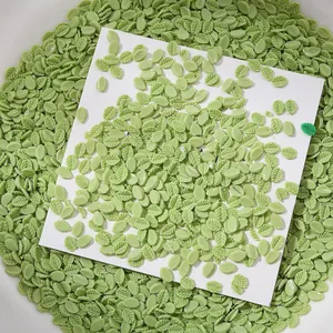 Détail macro de petits charmes d'art d'ongle en forme de feuilles vertes sur carte.