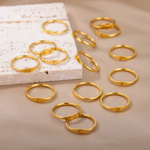 Collection of minimalist gold rings with engraved alphabet letters on stone