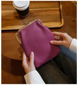 Detail shot of a purple pebbled leather kiss-lock phone bag featuring a gold chain strap