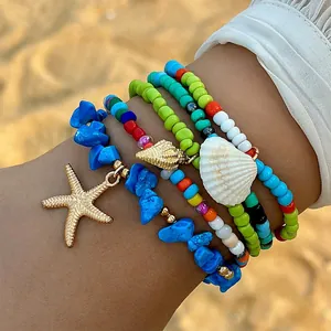 Detailopname van een Boheemse kralenarmbandenset met gouden zeester- en schelp-bedeltjes