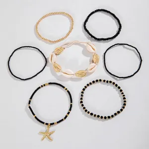 Set van zeven bohemian kralenarmbanden met gouden zeester bedeltje en schelpdetails